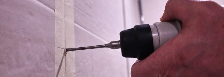 Hand bohrt mit Bohrmaschine in Fliese